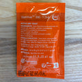 An orange fermentis SafAle BE-134 dry yeast sachet with white text, photographed flat on a light wood grain surface.