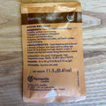A single packet of SafAle BE-256 active dry yeast by Fermentis Lesaffre, shown flat on a light wood background. The packet is brown with black text detailing the product's ingredients, characteristics, dosage, and pitching instructions.