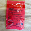 A red SafAle US-05m dry ale yeast packet by Fermentis s.A. Lesaffre, displayed flat on a light wood background.