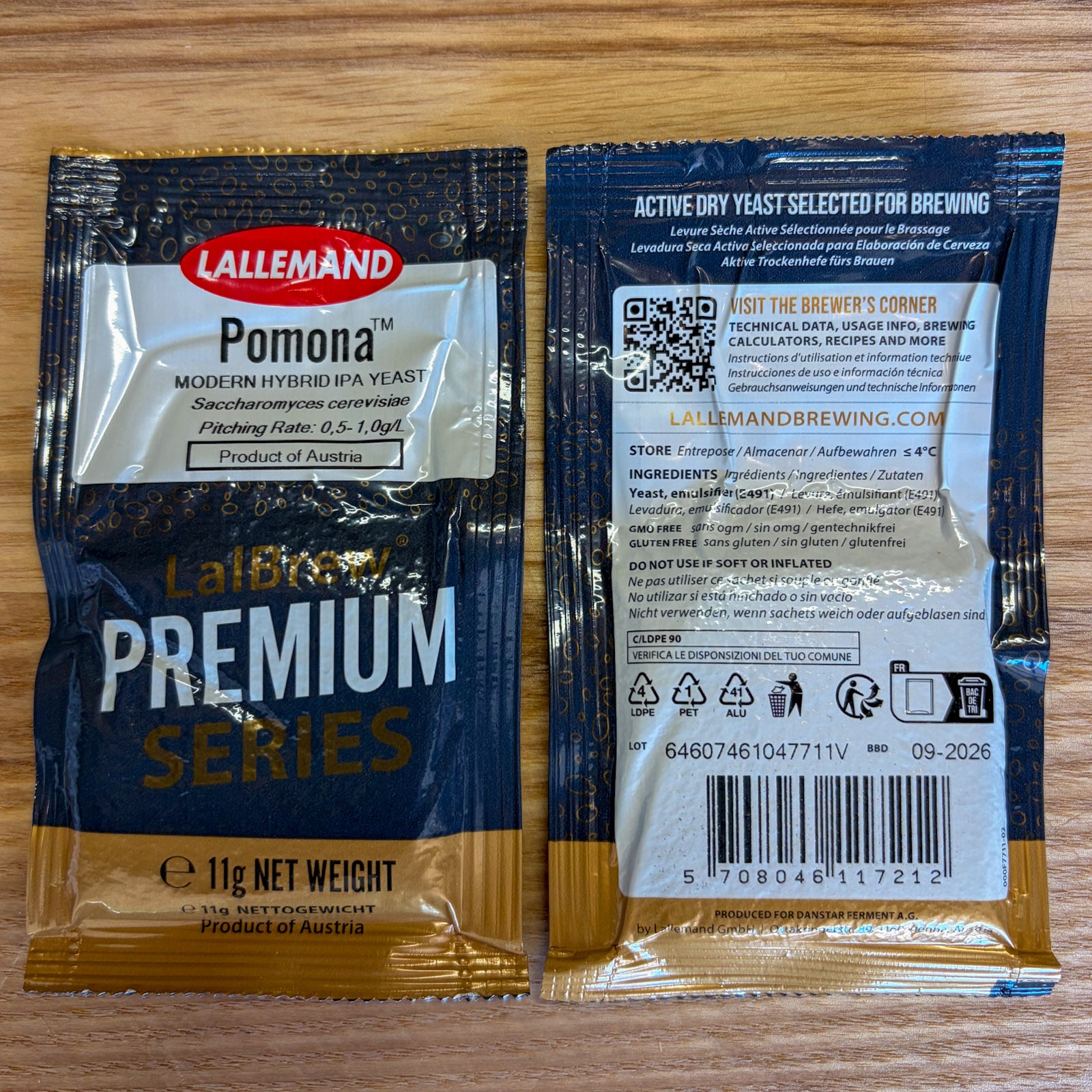 Two sealed packets of Lallemand lalbrew Pomona modern hybrid IPA active dry yeast shown side by side on a wooden surface, with the front and back packaging visible.