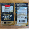 Two Lallemand Abbaye Premium Series ale yeast packets shown on a wooden surface, with the front and back packaging visible.