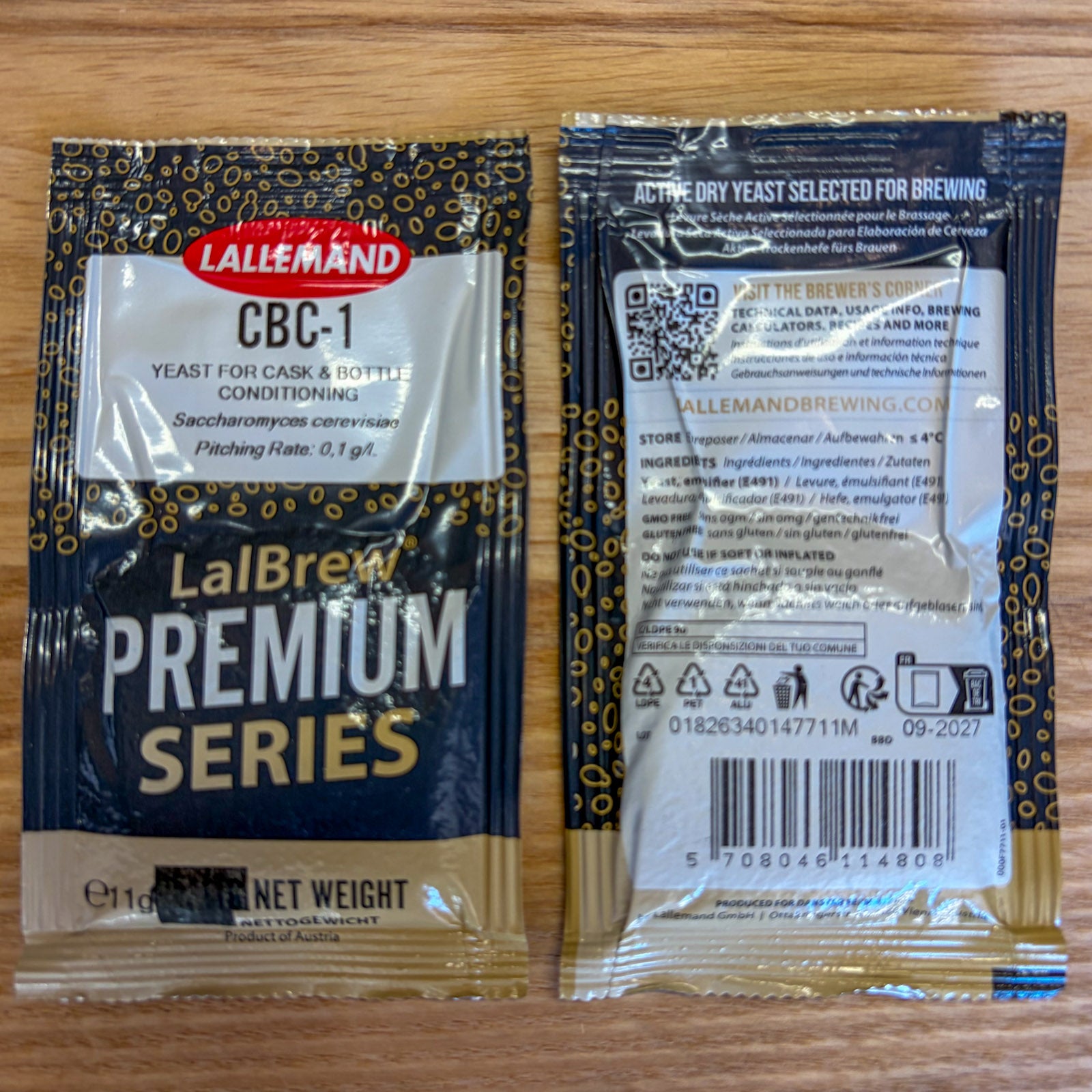 Two Lallemand CBC-1 LaBrew Premium Series yeast packets shown on a wooden surface, with the front and back packaging visible.