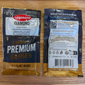 Two Lallemand Diamond Lager Yeast packets shown front and back on a light wood surface. The front packet is black with gold and white text, and the back packet shows brewing information, QR code, ingredients, and barcode.