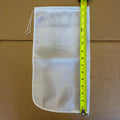 A 15”x8” nylon bag with a drawstring, shown on a brown cardboard background with a yellow tape measure placed vertically next to it for size reference.