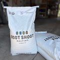 A bag of root shoot malting genie pale ale sack with other grain bags nearby in a garage setting