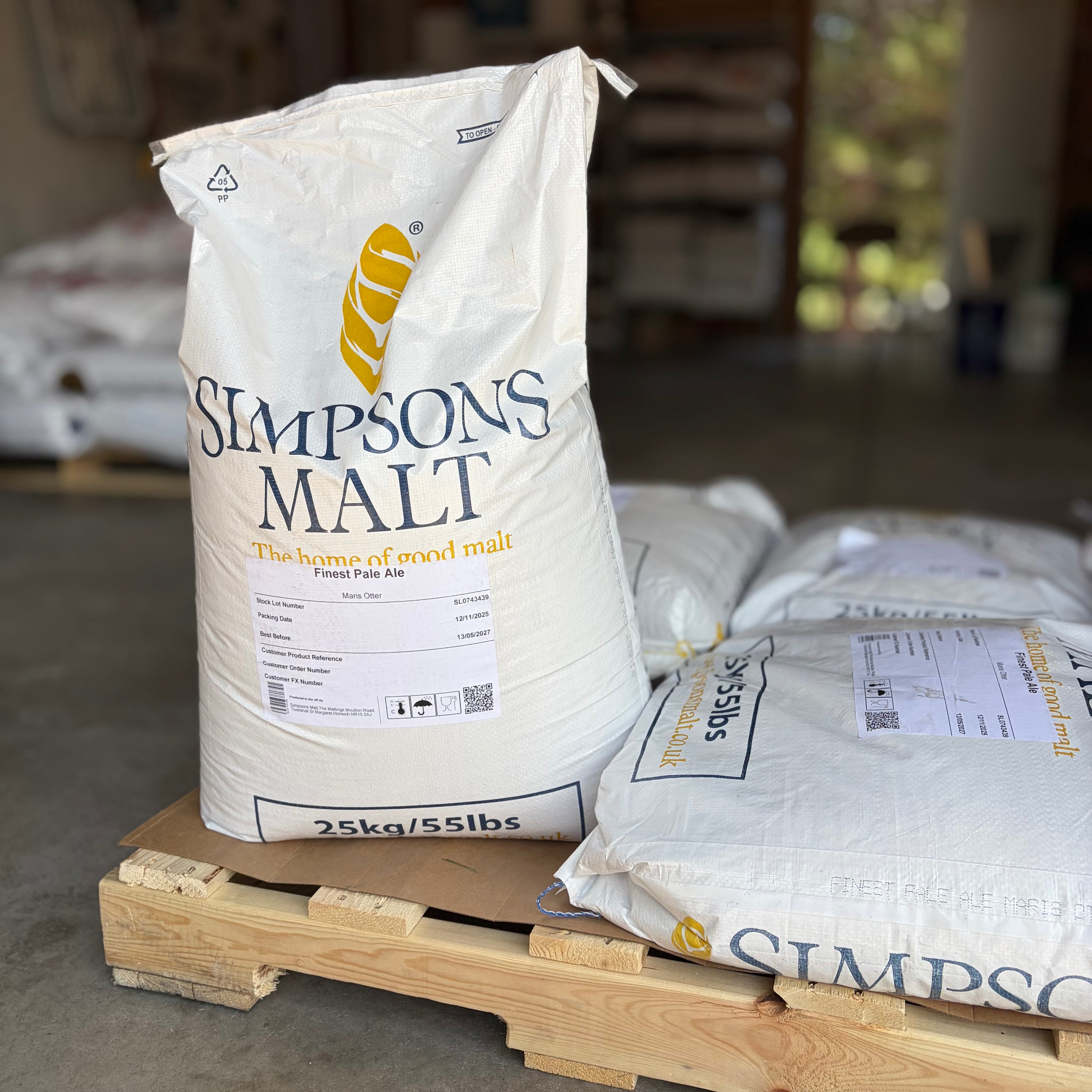 A pallet of Simpsons finest pale ale Maris otter sacks with one bag standing up to show the label in a garage setting