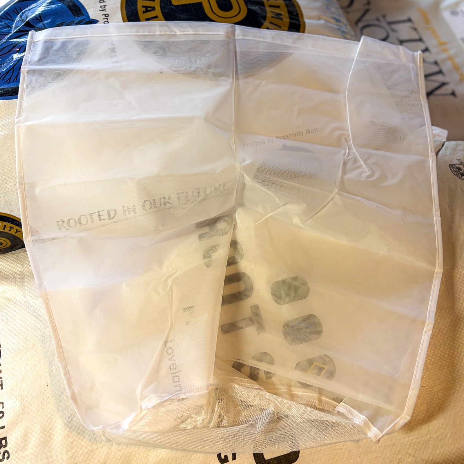A large nylon bag used for brewing resting on grain sacks to compare size
