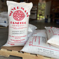 Bags of weyermann Vienna malted barley on a pallet, with one standing up showing the label in a garage setting