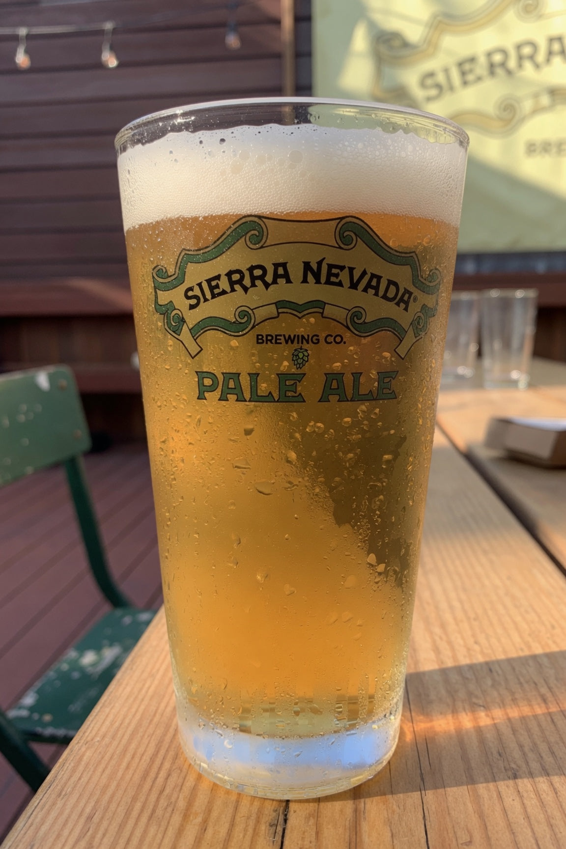 glass of pale golden beer showing sierra nevada pale ale on a sunny brewery patio with cascade hops