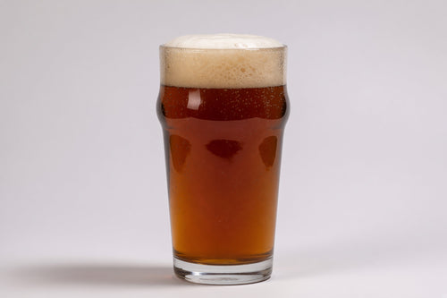 a pint glass with amber colored beer and a tan head in a studio setting made with dingemans aromatic malted barley