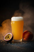 Glass of hazy beer with a peach and passion fruit in a dark, steamy place with nectaron hops