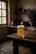 A frosted glass beer stein mug filled with golden beer and topped with white foam, set on a rustic wooden table in a dimly lit, vintage-style room with stone walls and copper pots in the background with strisselspalt hops.